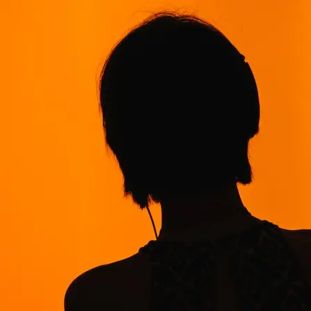 silhouette of woman standing in front of orange wall